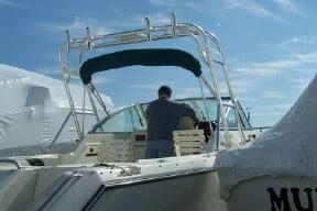 Atlantic Towers Arch installed on a Pursuit 2460 Denali boat with a person at the helm under a blue sky.