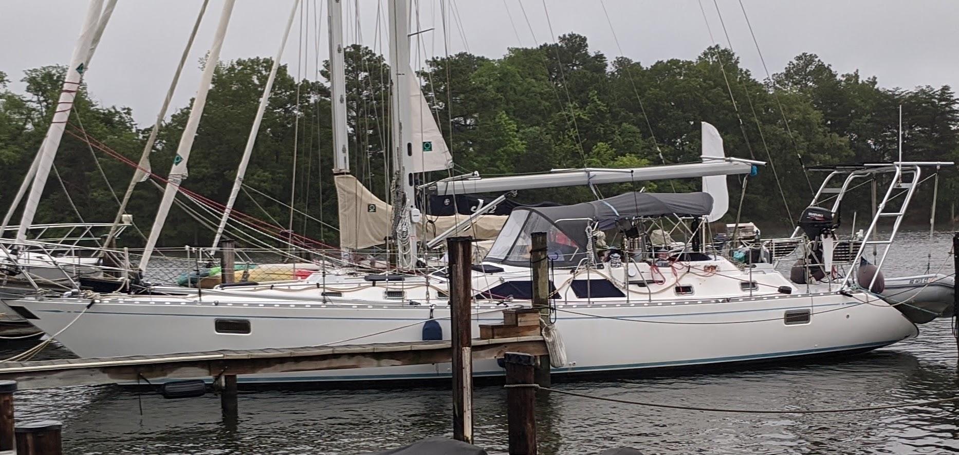 White Hylas Yachts sailboat docked with rigging and sails, featuring Atlantic Towers arch with mounted motor and canvas cover.