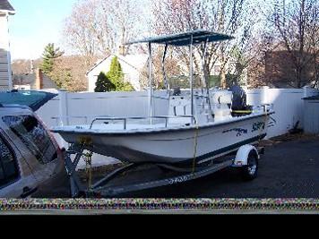 Carolina Skiff Center Console boat equipped with Atlantic Towers T-Top, parked on a trailer in a driveway.