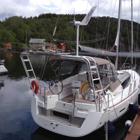 Jeanneau sailboat with Atlantic Towers Aft Deck Top installed, docked in calm water near forested shore.
