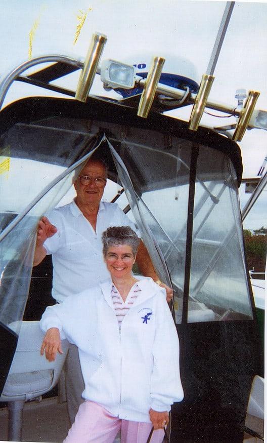 An older man and woman pose on a Wellcraft 250 Sportsman boat, featuring the Atlantic Towers Arch installed.