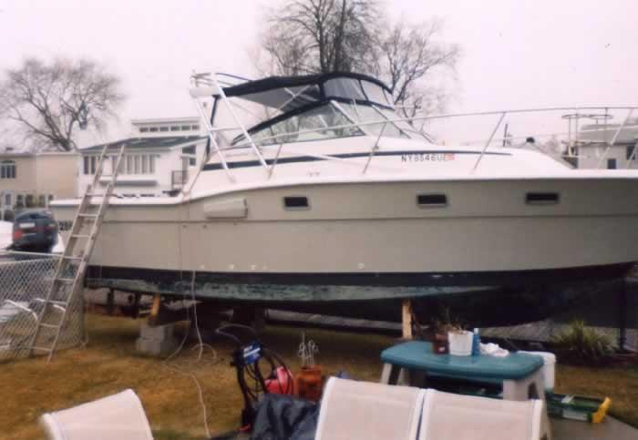 Aquasport 286XF boat with Atlantic Towers Arch installed, resting on blocks outdoors near lawn furniture.
