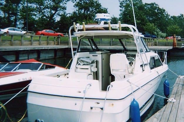 Rear view of Bayliner 2452 Ciera boat with installed Atlantic Towers Arch docked at a wooden pier with blue fenders attached.