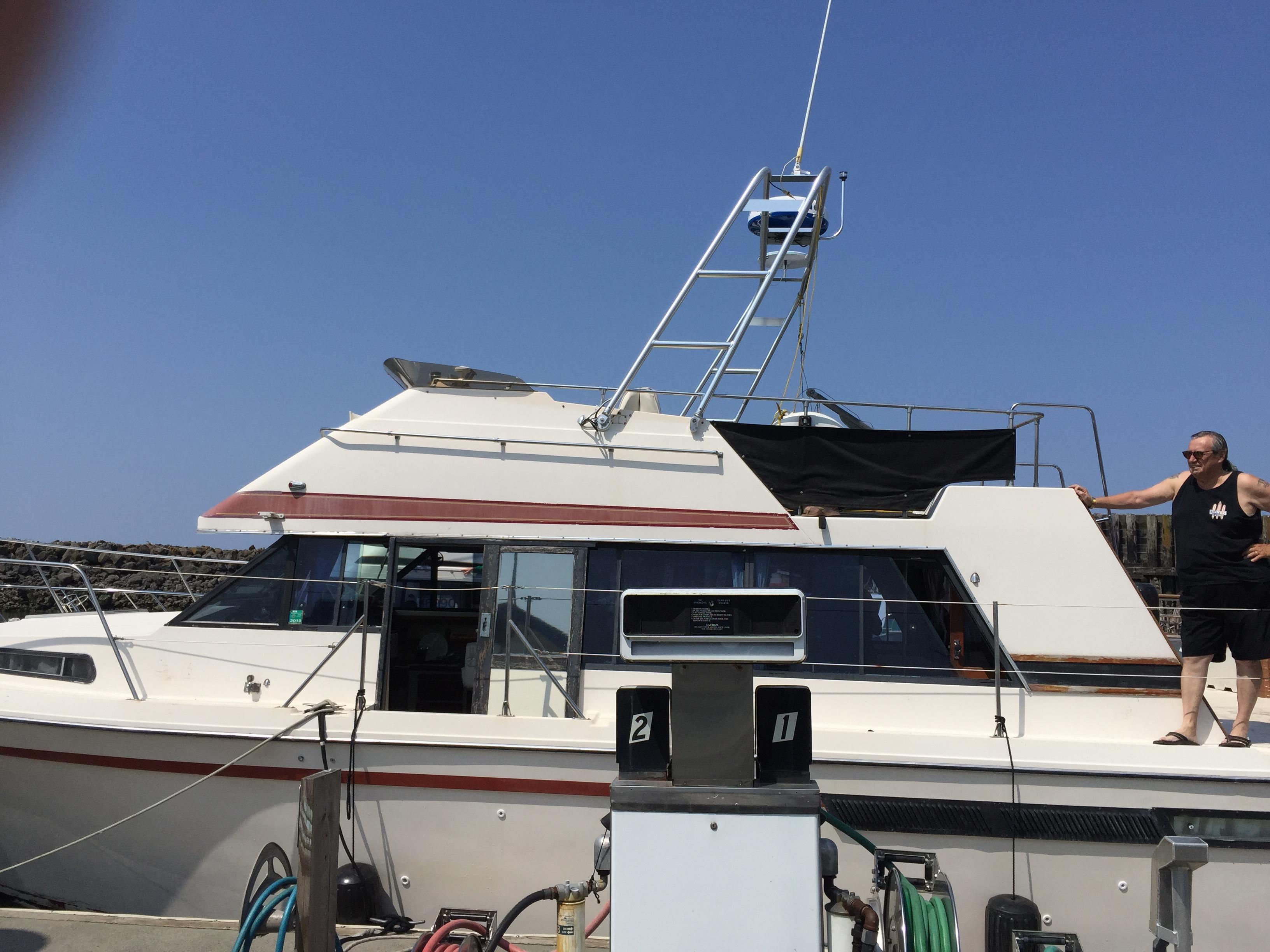 A Bayliner boat featuring an Atlantic Towers Arch, docked with a man standing on the deck.