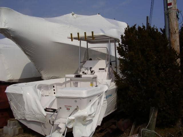 Trophy 20 Center Console boat with an installed Atlantic Towers T-Top parked near wrapped boats and trees.