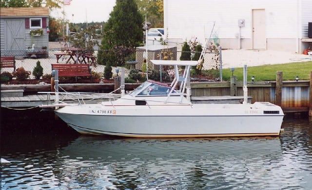 White IMP boat with Atlantic Towers Top installed docked by a wooden pier near a residential area.