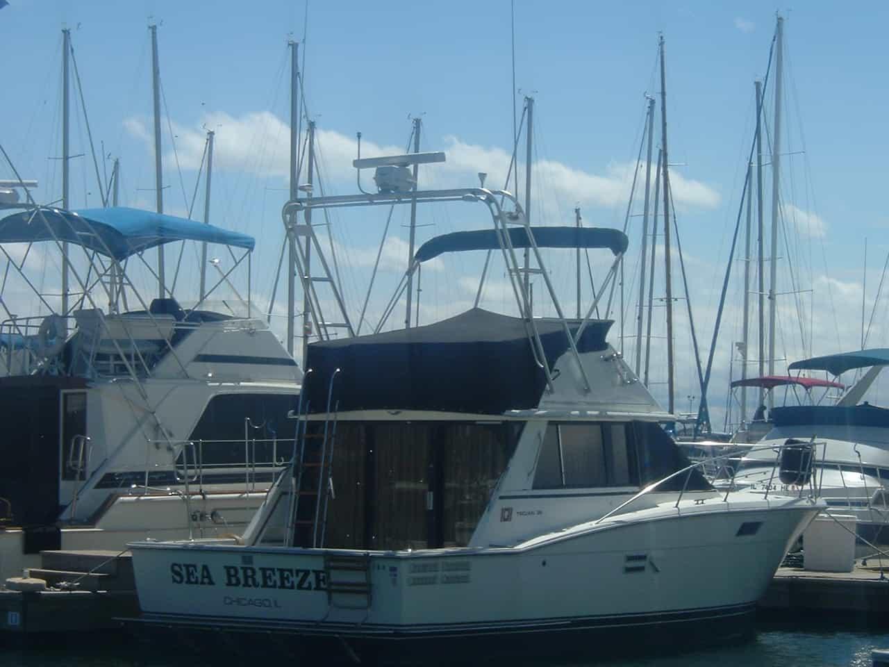 Trojan F36 Convertible boat docked with Atlantic Towers Arch and blue canvas covers on upper deck and controls.