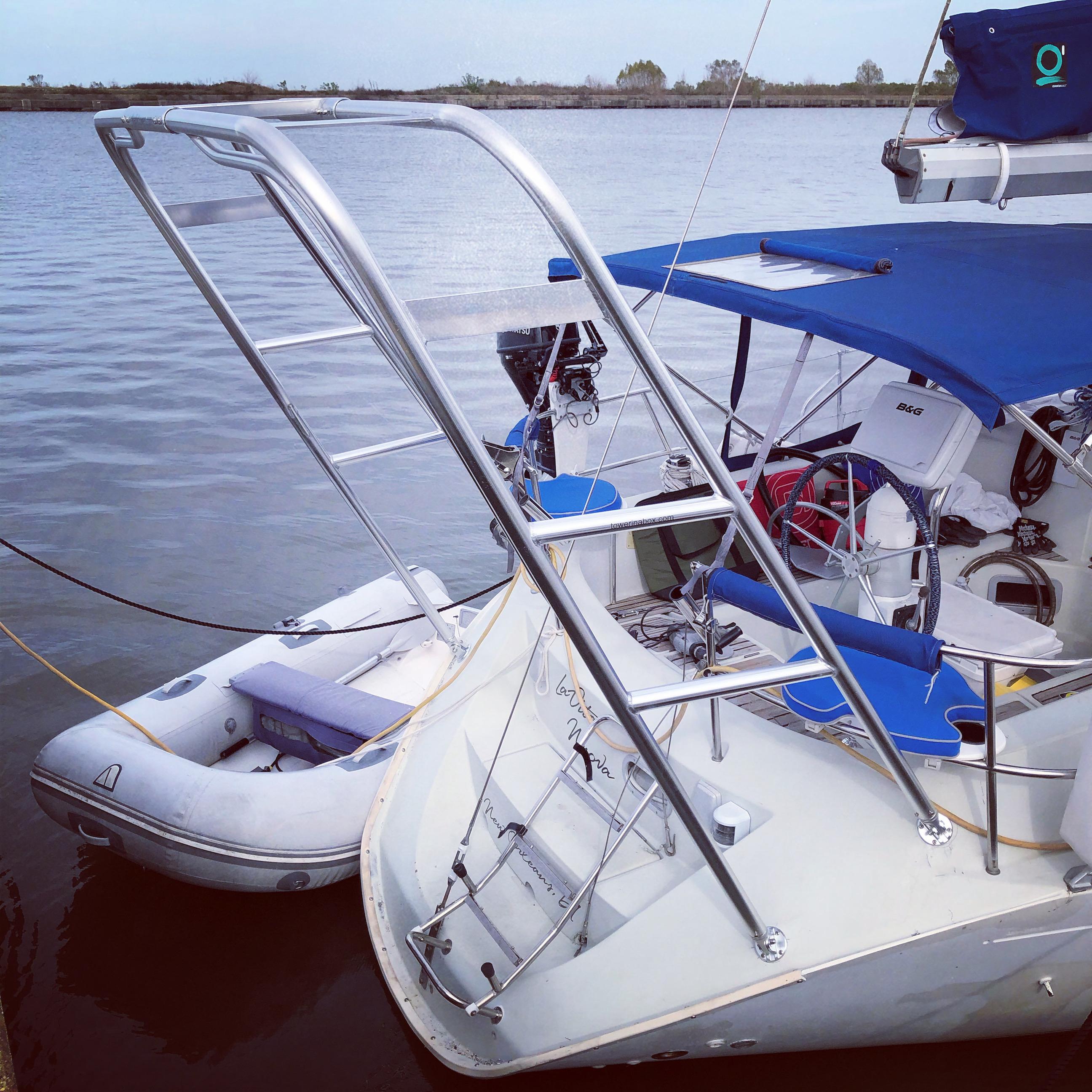 Atlantic Towers arch installed on the stern of a Beneteau sailboat with a dinghy tied alongside on calm water.