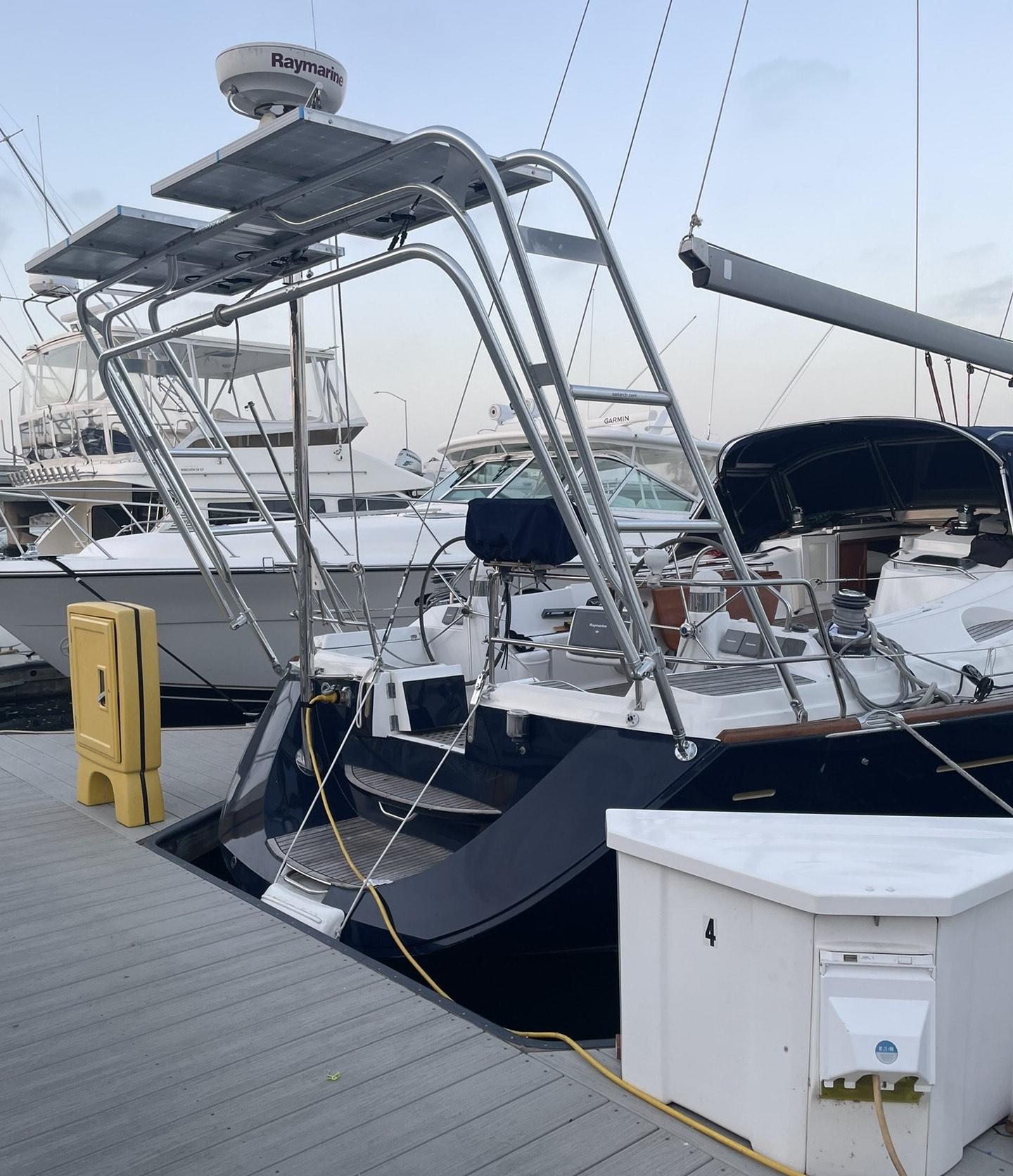 Atlantic Towers arch installed on the stern of a Jeanneau sailboat docked at a marina next to other boats.