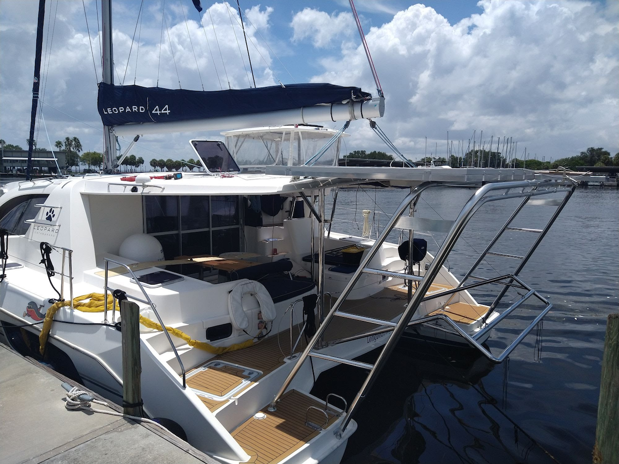 Leopard catamaran docked with Atlantic Towers Arch stainless steel frame over the rear deck under a partly cloudy sky.