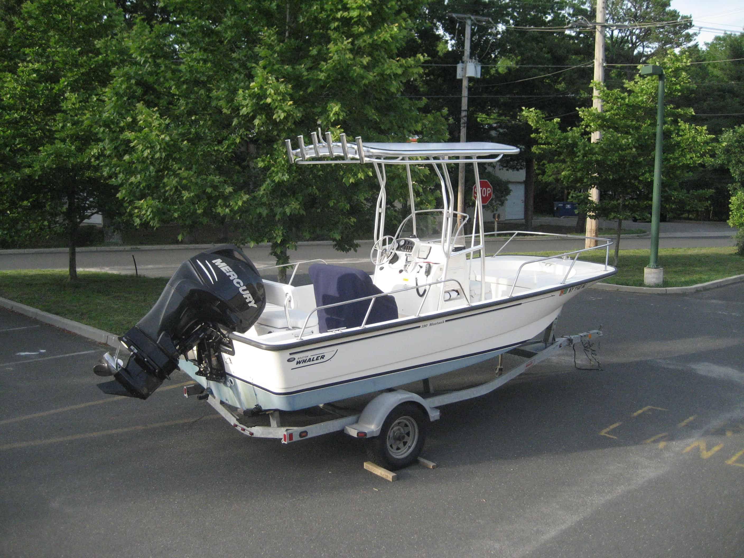 Atlantic Towers T-Top installed on a Boston Whaler boat parked in a lot surrounded by greenery.