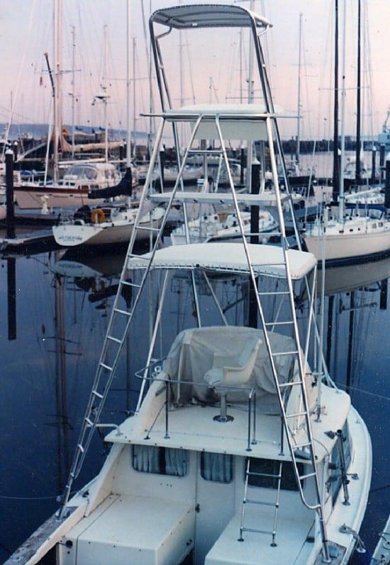 Bertram boat with installed Atlantic Towers Tuna Tower featuring multiple platforms and ladders at a marina.