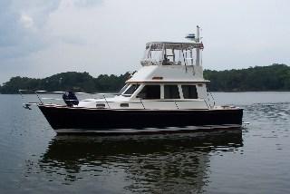Sabreline 36 Sedan boat on water with Atlantic Towers Top installed over the flybridge and trees in background.
