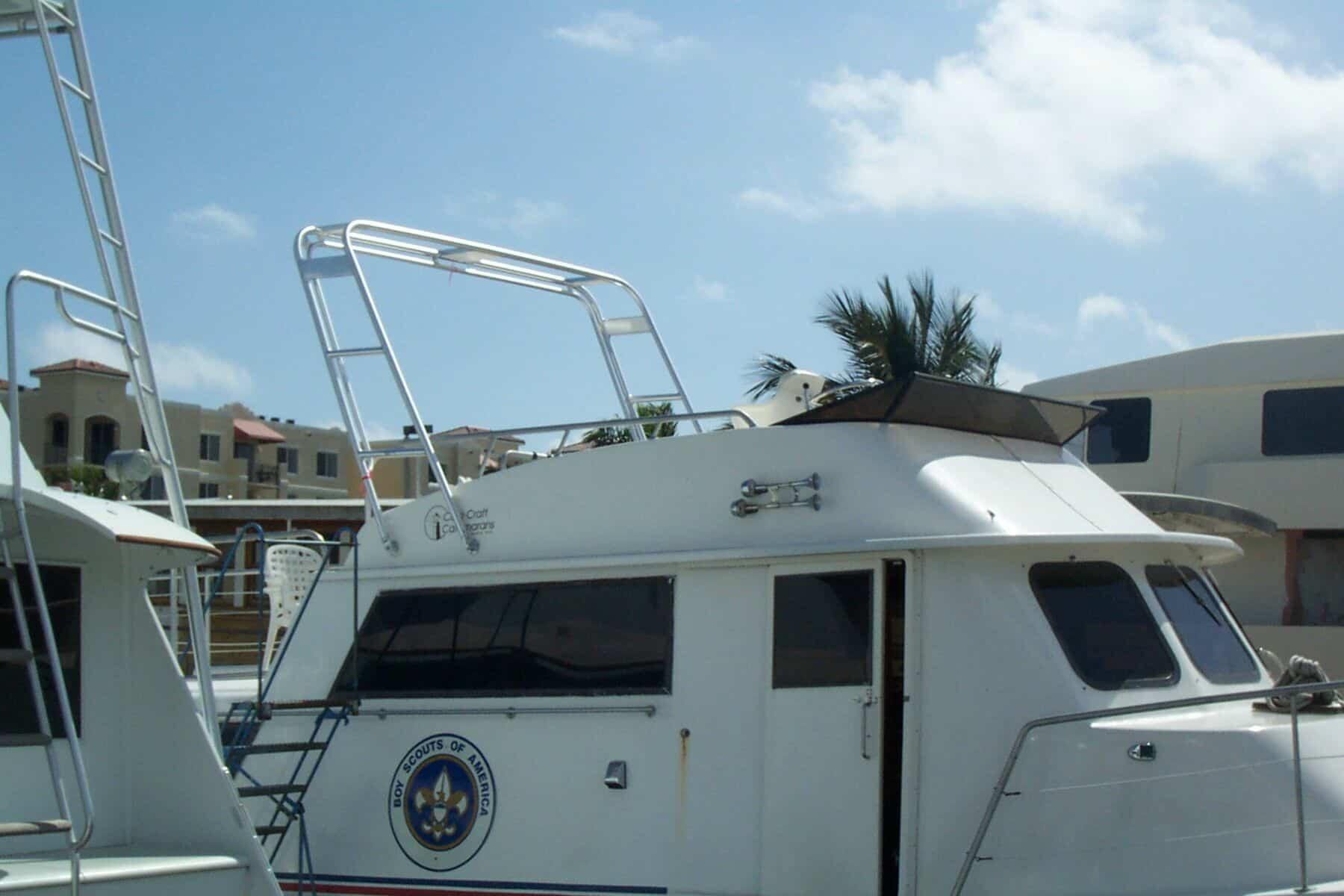 Atlantic Towers arch installed on the roof of a Carrie Craft 60 House Boat docked near buildings under a partly cloudy sky.