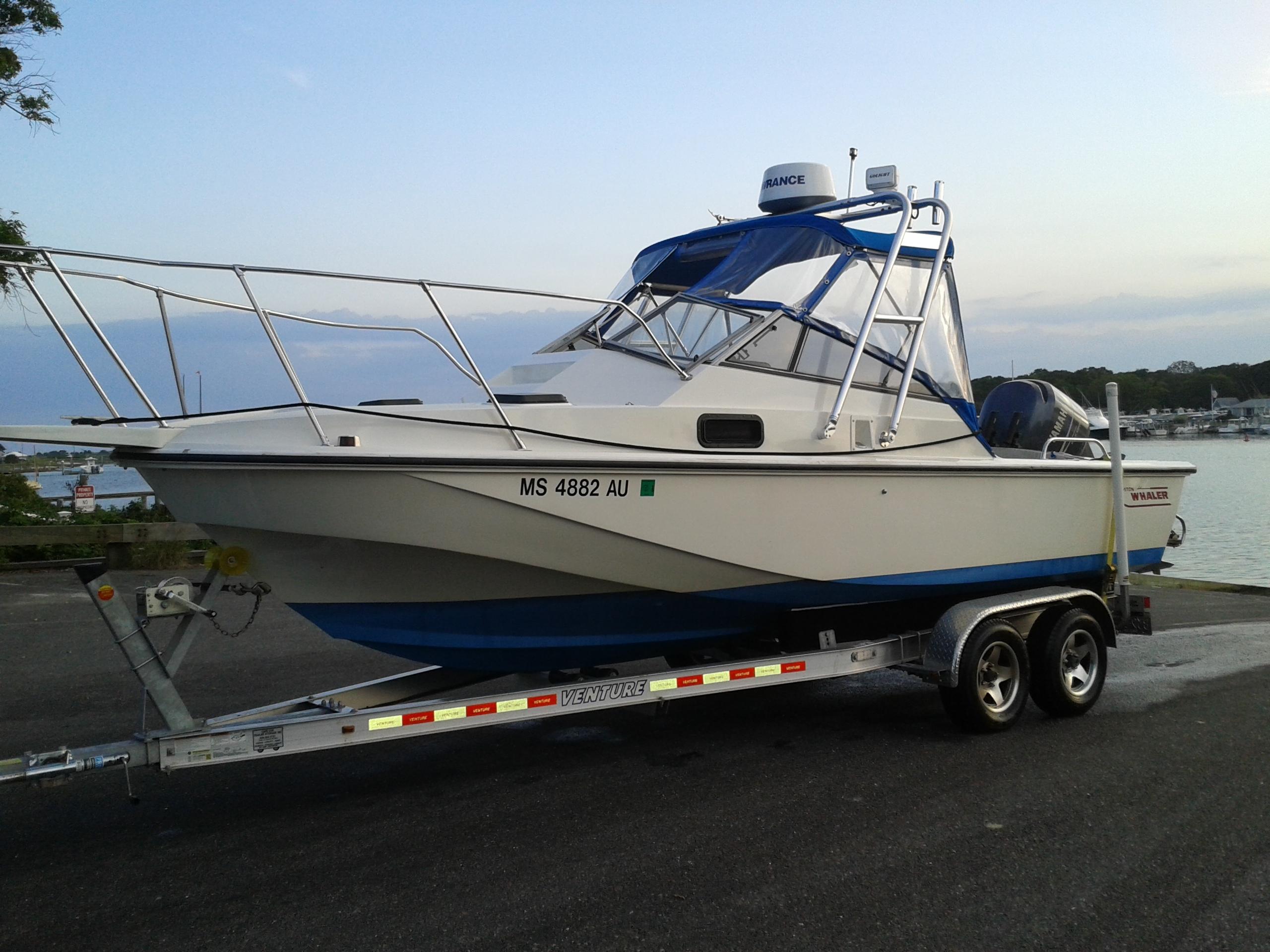 Atlantic Towers boat on a trailer, parked by the water with calm skies and a marina in the background.