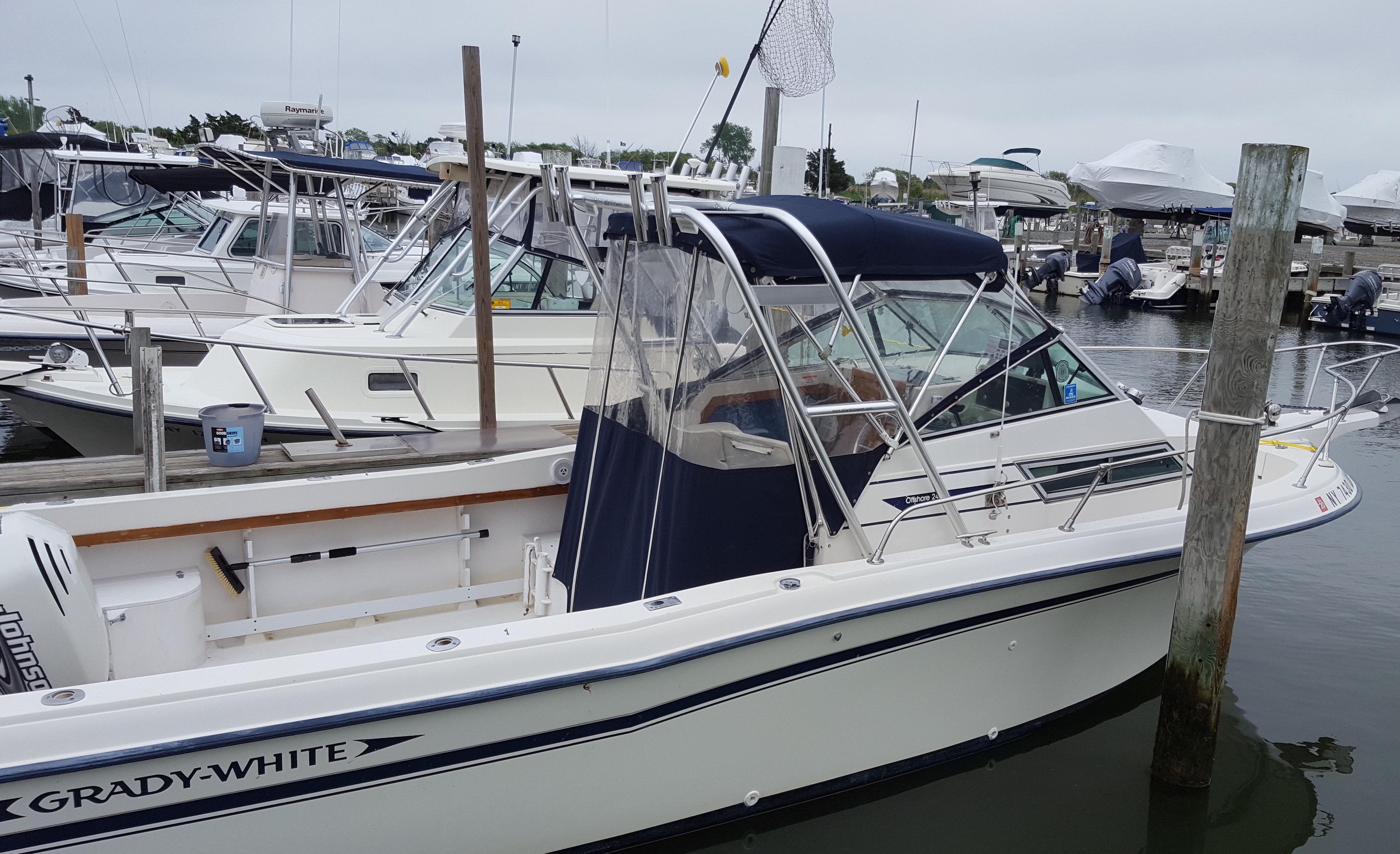 Grady White boat docked, featuring Atlantic Towers Top with navy canvas and clear side panels over the helm area.