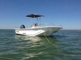 Atlantic Towers boat anchored in calm waters, featuring a T-top and console for navigation.