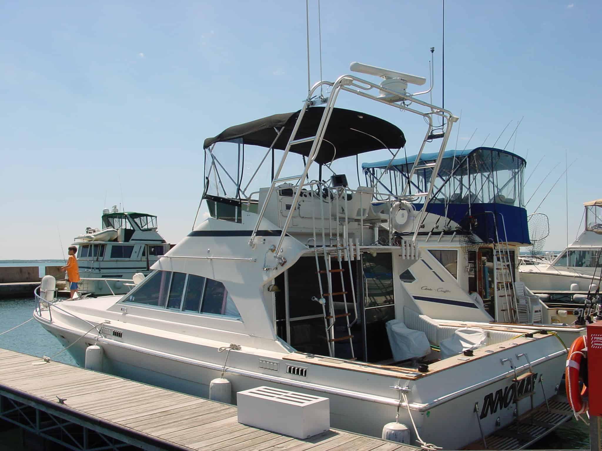 Atlantic Towers Arch installed on an Infinity 38 F/B boat at a marina, with fishing activity in the background.