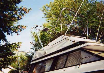 Atlantic Towers Arch installed on the flybridge of a Bayliner Saratoga Flybridge boat docked near trees on a sunny day.