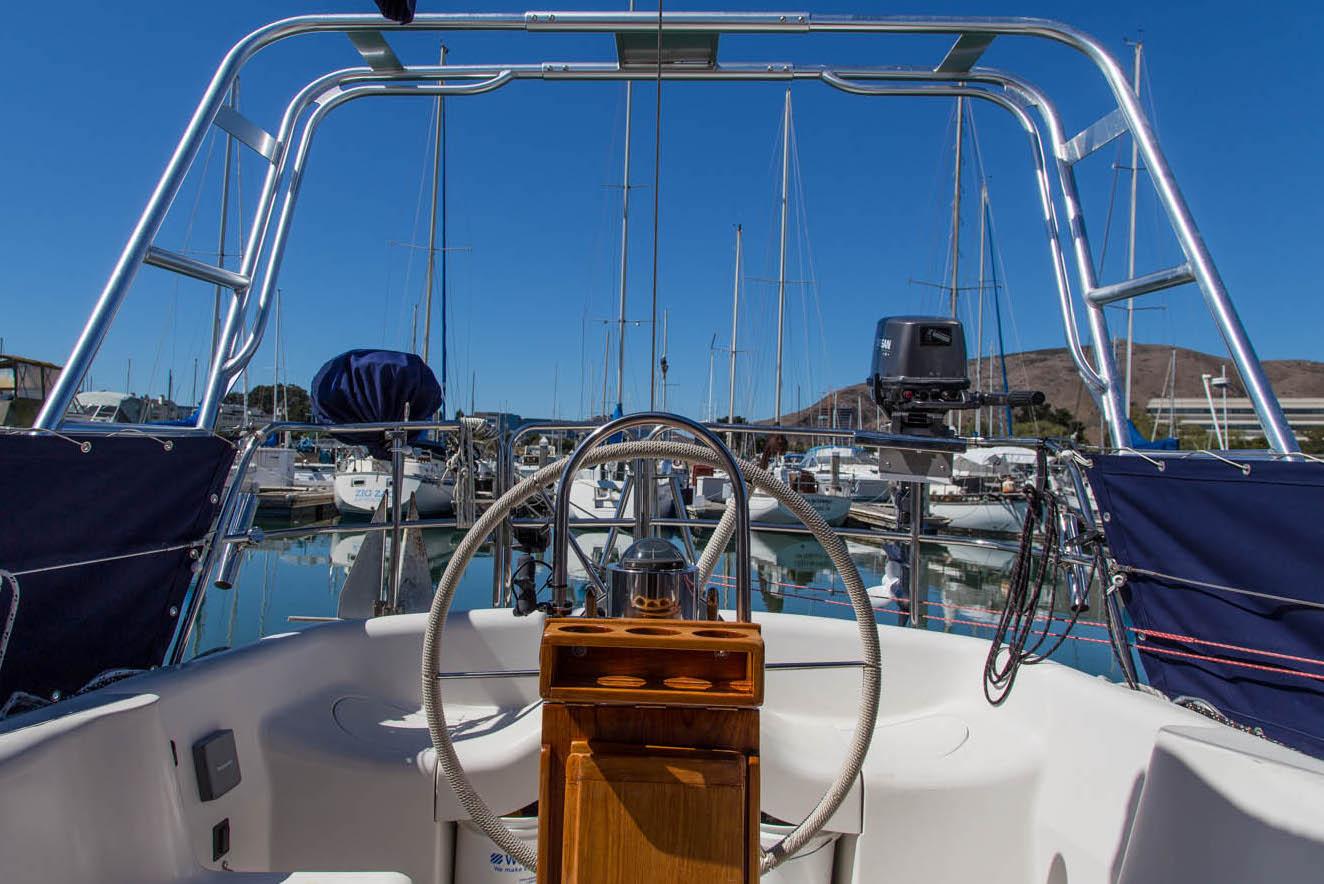 View from the cockpit of a boat featuring an Atlantic Towers Arch, overlooking a marina filled with sailboats.