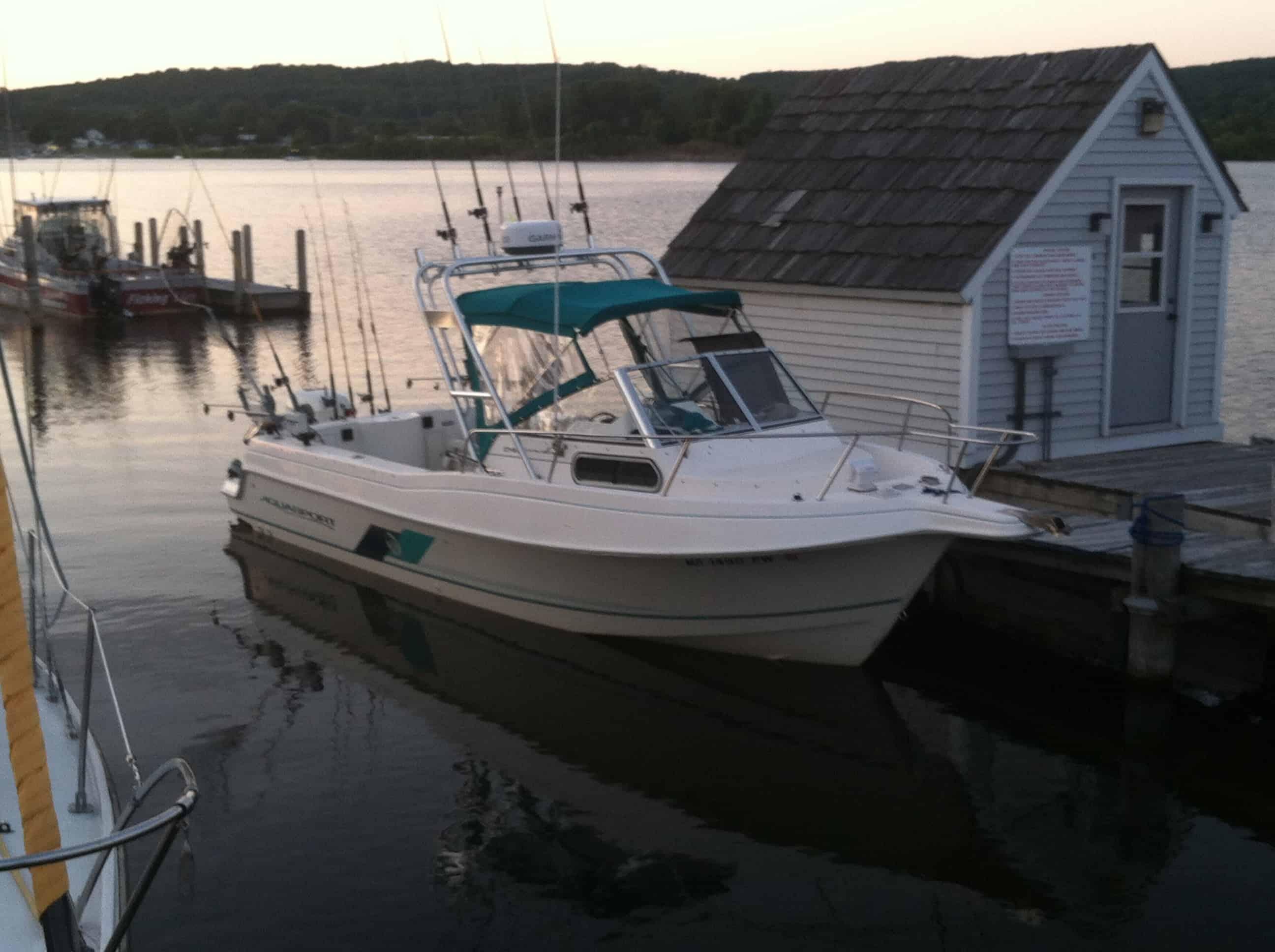 White fishing boat docked alongside a small boathouse at sunset, equipped with Atlantic Towers Top structure and fishing rods.