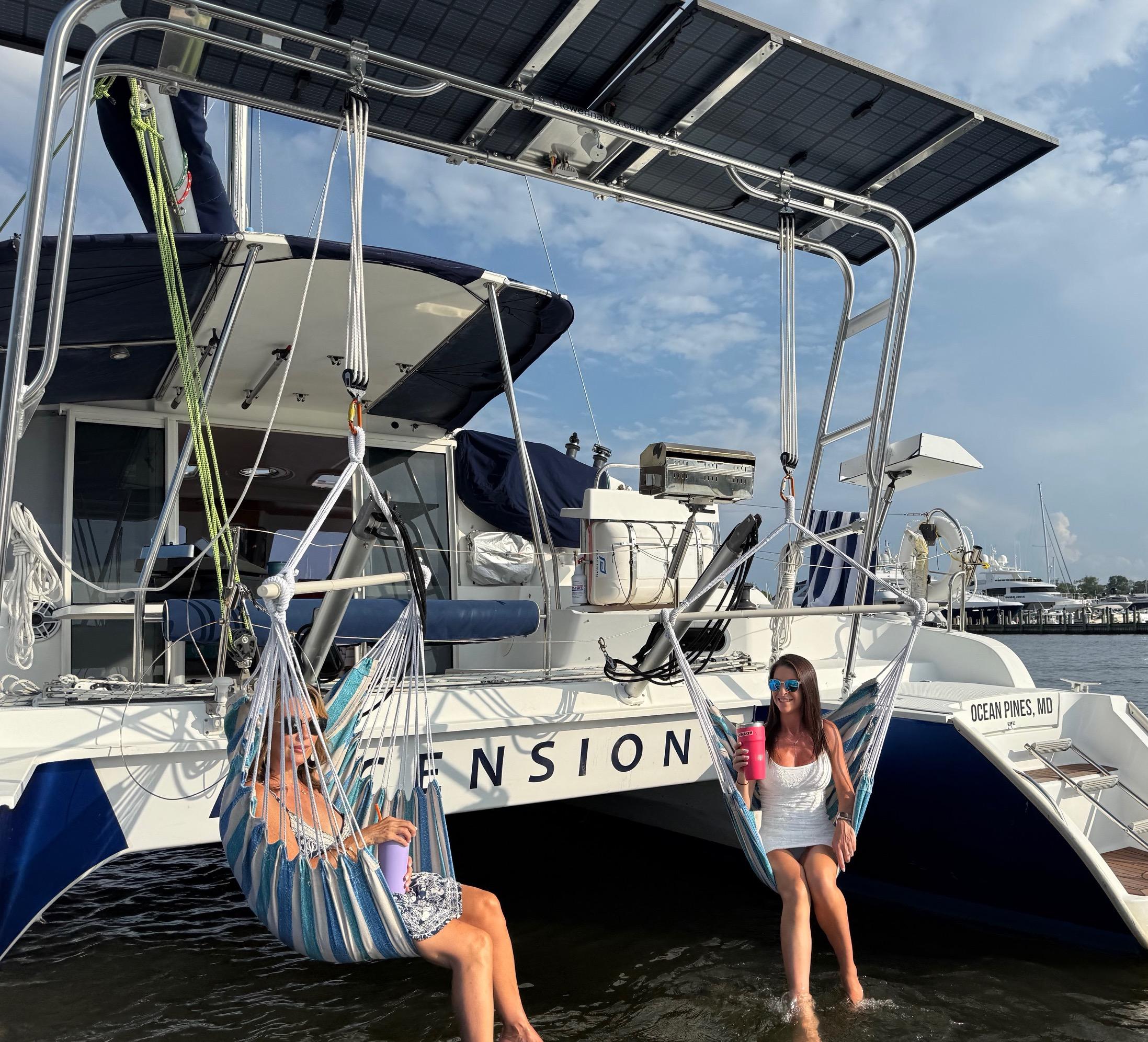 Two women relax in hammock swings beneath the Atlantic Towers Arch on a Fountaine Pajot boat at the marina.