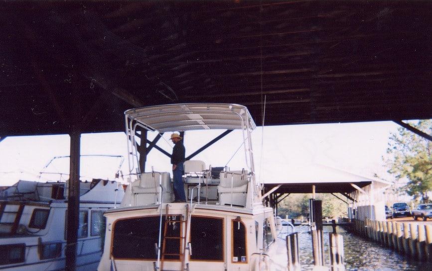Atlantic Towers Top on an Egg Harbor 38 boat with a person standing on the upper deck under a covered slip.