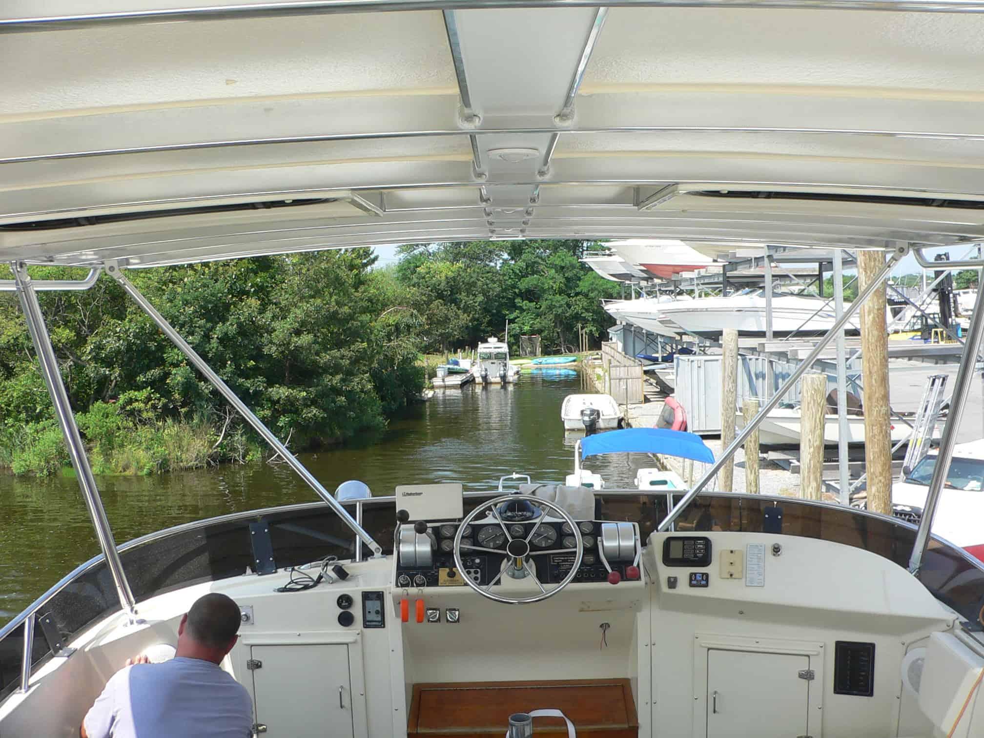 View of the helm station under the Atlantic Towers Top on a Californian/Carver 4836 Motor Yacht with person working on the left side.
