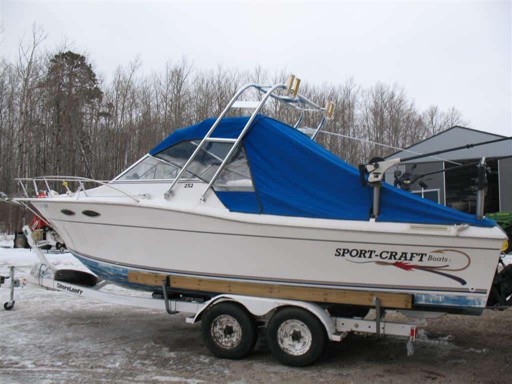 Atlantic Towers Arch installed on a Sportcraft boat with a blue cover, parked on a trailer in a winter setting.