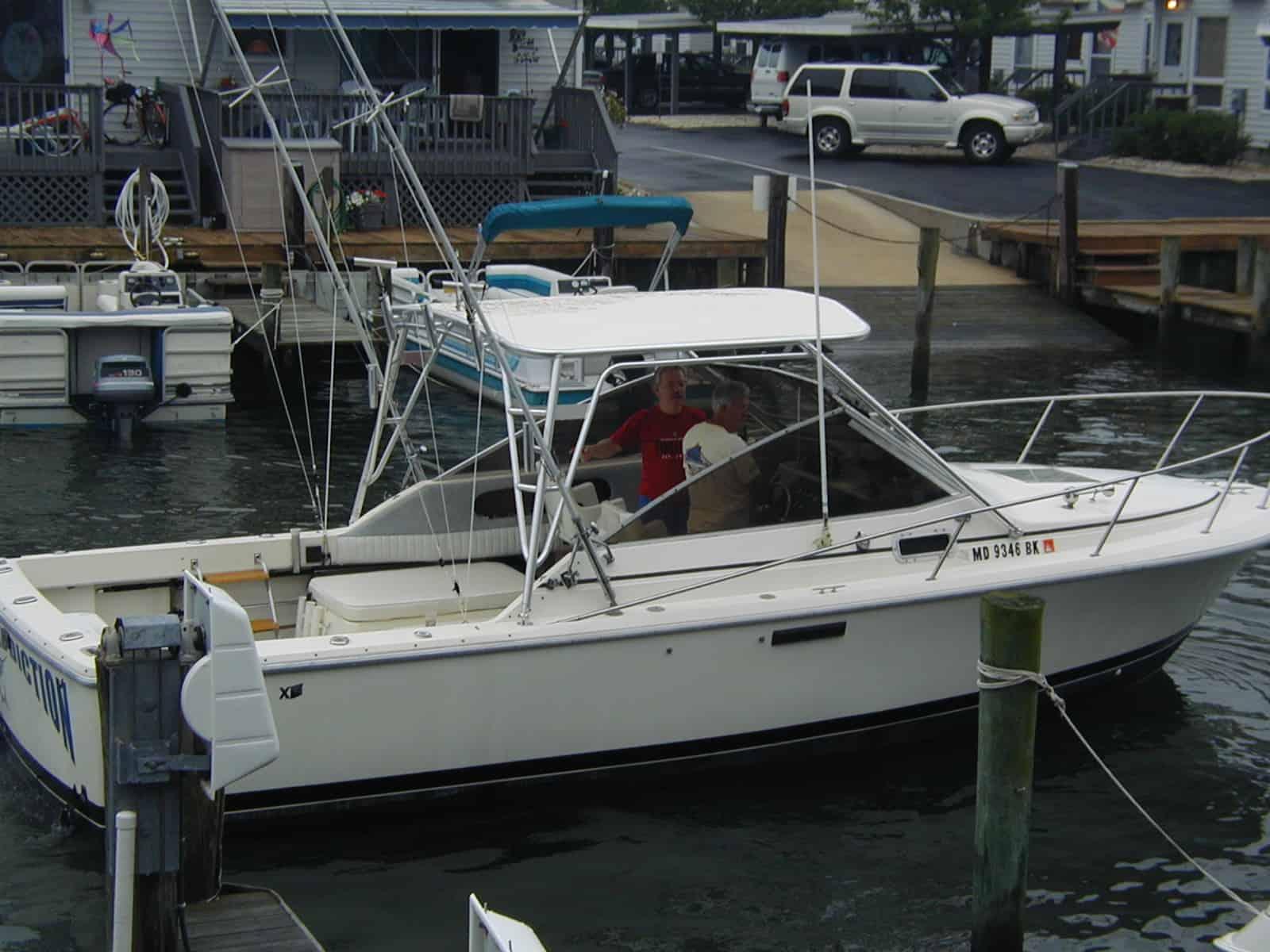 White Phoenix 27 Weekender boat docked with two people aboard and Atlantic Towers Top installed over the helm.