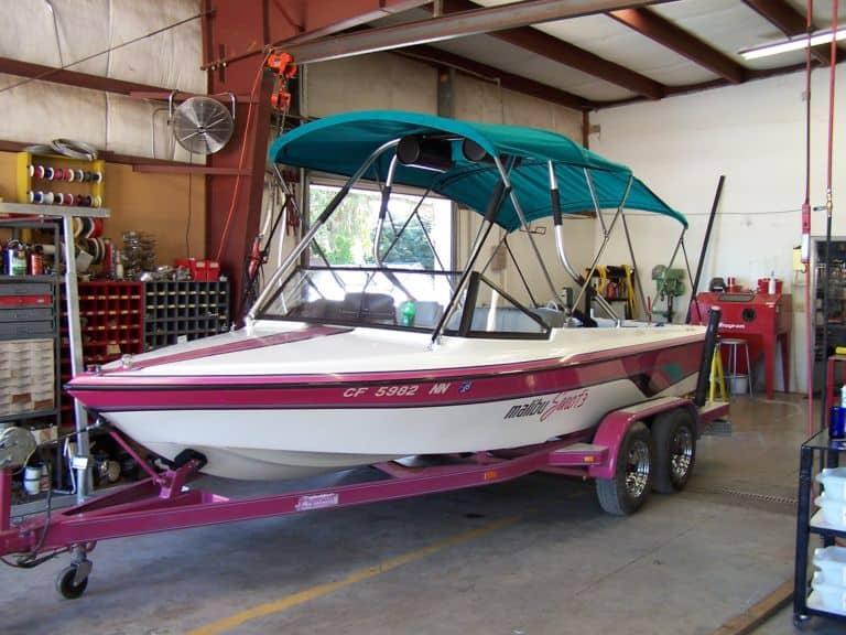 Malibu Euro F3 boat with teal canvas top and Atlantic Towers Air Tower installed, on pink trailer inside workshop.