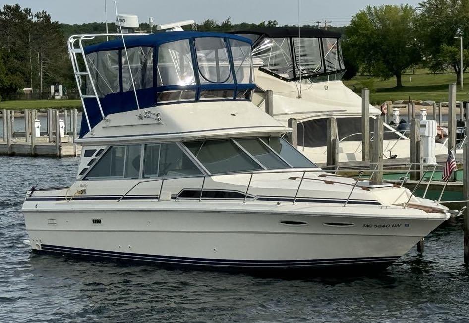 White Sea Ray boat docked with blue Atlantic Towers Arch canopy and surrounding marina docks and boats in background