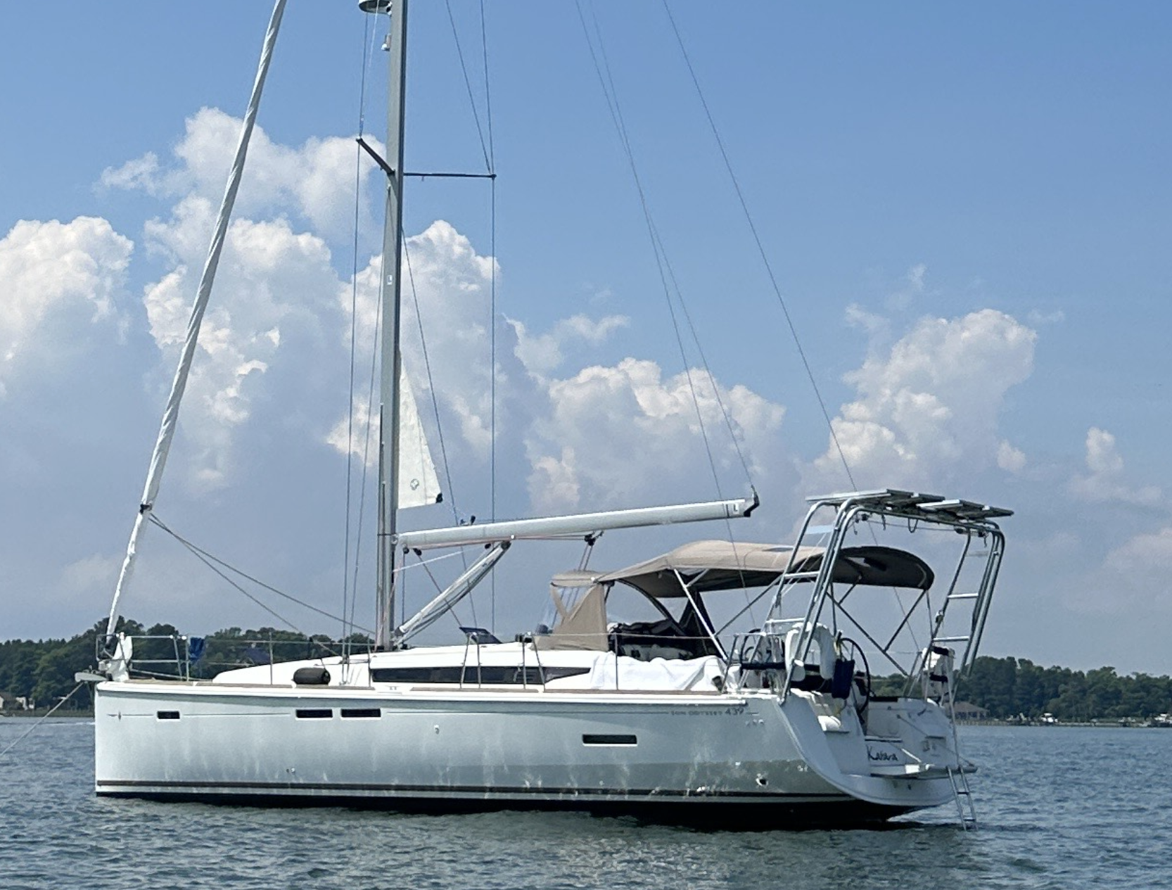 Sailboat with Atlantic Towers Arch installed at the stern, anchored in calm water under a partly cloudy sky.