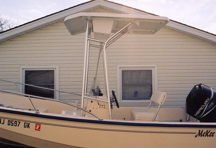 McKee Craft Console boat equipped with Atlantic Towers T-Top and Mercury outboard motor parked near a house wall