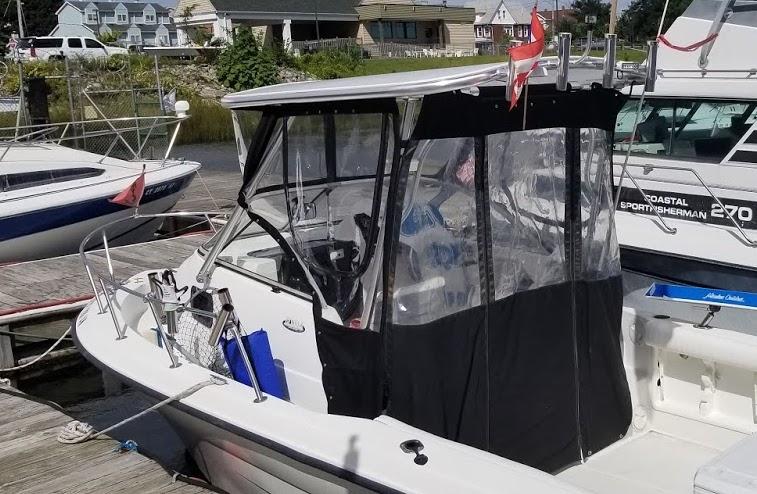 White Hydra Sports boat docked with black canvas and clear plastic surrounding Atlantic Towers Top installed on the helm area.