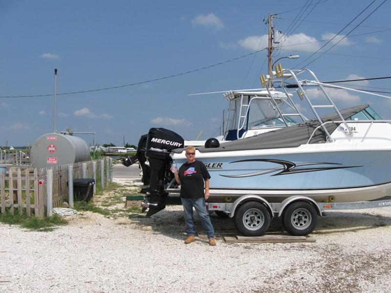 Atlantic Towers Arch installed on an Angler Boats 204 W/A, with a Mercury outboard motor and a person standing nearby.