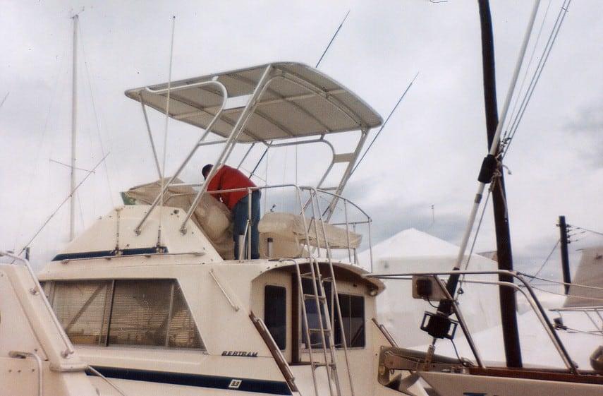 Bertram 33 FB boat with a person on the upper deck, featuring an installed Atlantic Towers Top canopy and railings.
