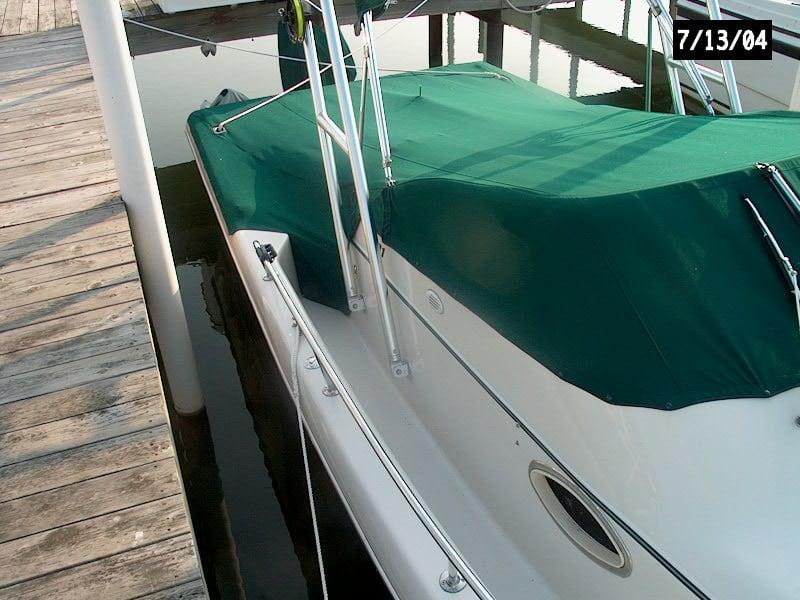 Pro Line 231 W/A boat docked with a green canvas cover and Atlantic Towers arch installed near a wooden pier.