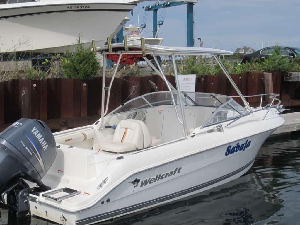 Wellcraft V-21 Steplift boat named Sabeja with Atlantic Towers Top installed, moored at a dock near vegetation and other boats.