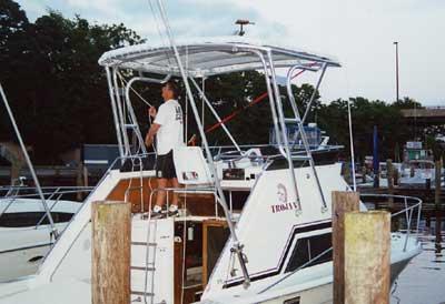 Atlantic Towers Top installed on Trojan 30 Sport Cruiser boat docked at marina with person standing under the tower.