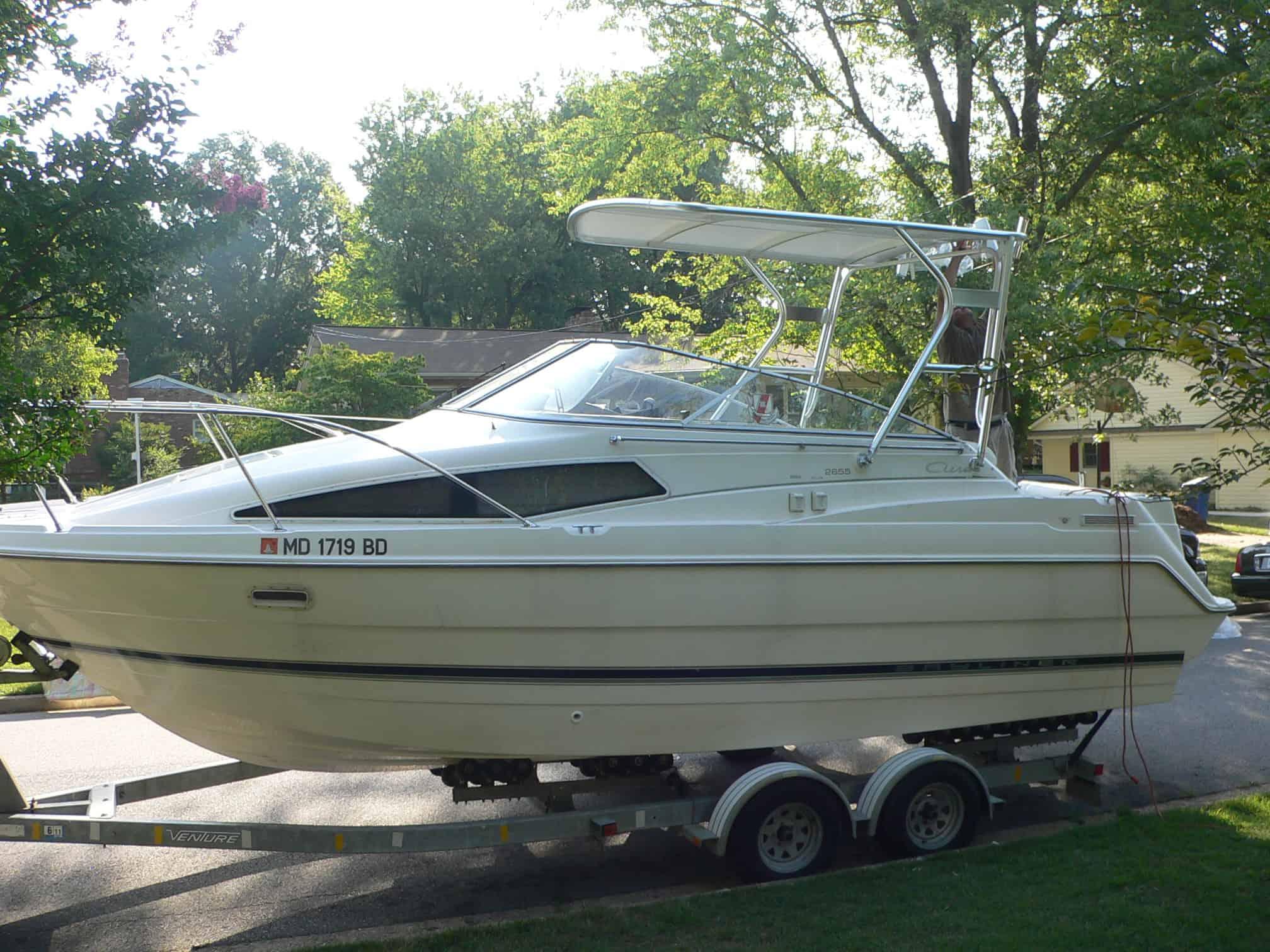 Atlantic Towers Top installed on a Bayliner 2655 Ciera Sunbridge boat parked on a trailer in a residential area.