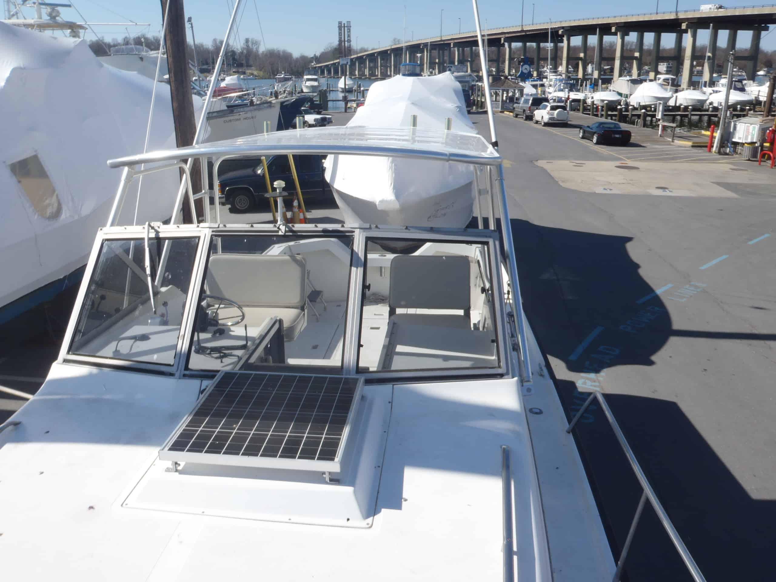 View of the bow and cockpit from above on an Alura 30 boat with Atlantic Towers Top in a marina parking area.