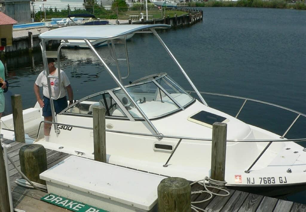 Atlantic Towers Top installed on a Century 2300 walkaround boat docked by a waterway with two people nearby.
