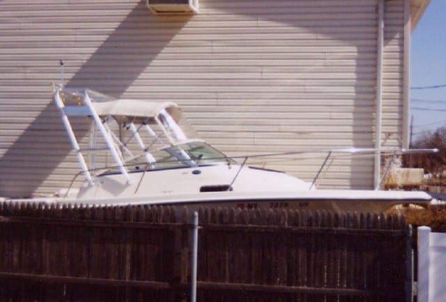 Atlantic Towers Arch installed on a white 2302 Trophy boat parked next to a building and behind a wooden fence.
