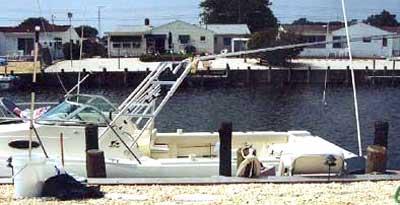 A Seamaster 2588 Walkaround boat featuring an Atlantic Towers Arch at the dock near residential buildings.