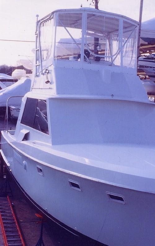 Hattaras 34 boat with an installed Atlantic Towers Top enclosure on the upper helm station docked on stands at a marina.