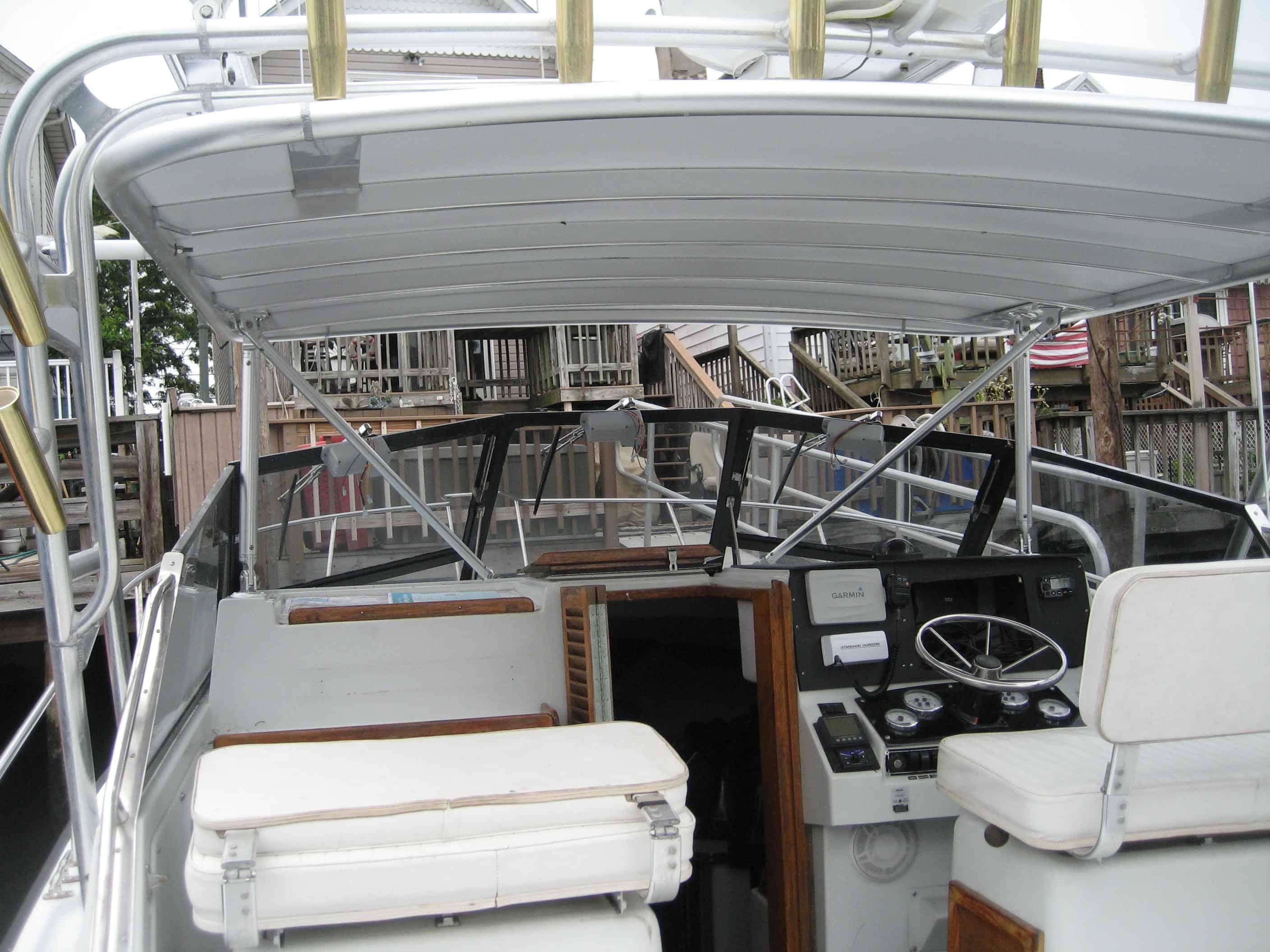 Interior view of a Rampage boat cockpit showing navigation instruments and a white cushioned helm seat under the Atlantic Towers Top canopy.