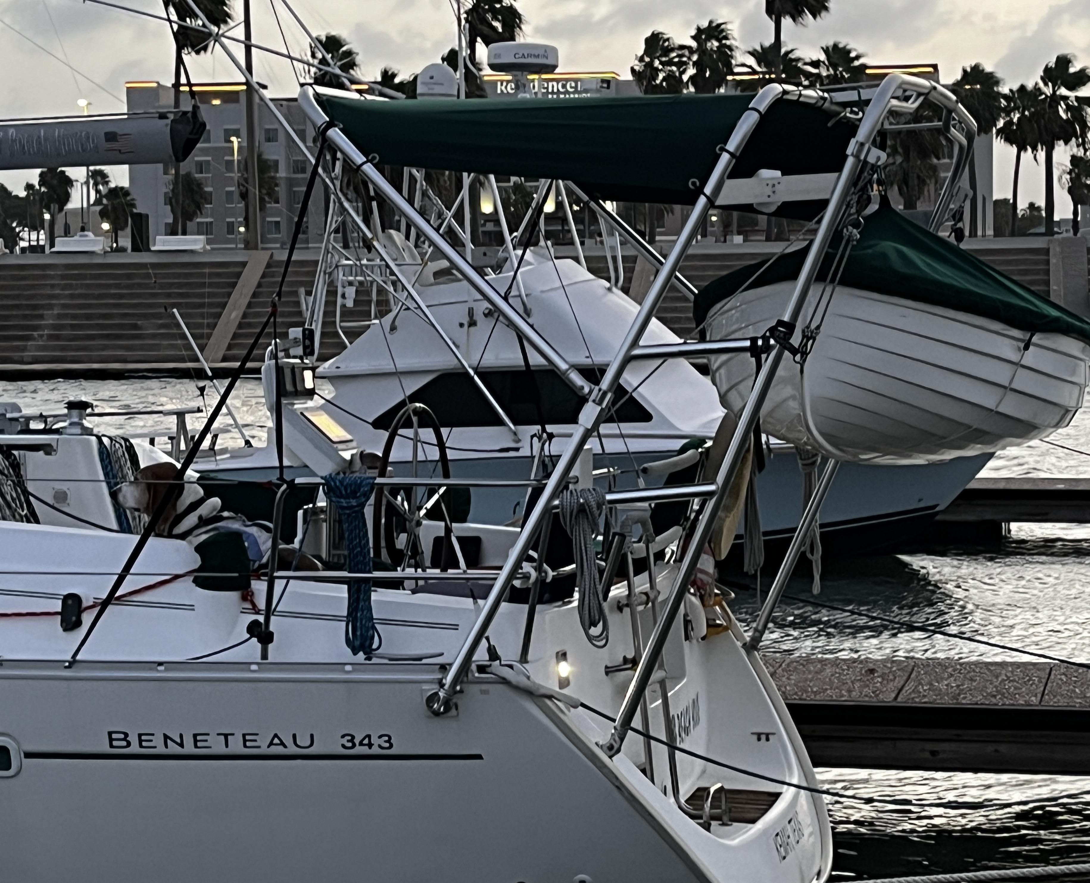 Atlantic Towers Arch installed on a Beneteau 343 boat, featuring a green cover and surrounded by other vessels in a marina.