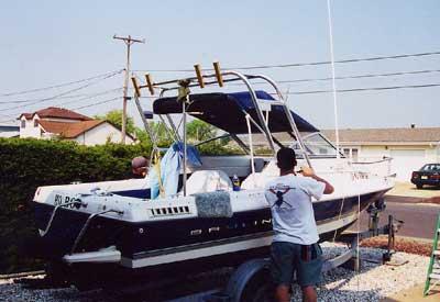 Atlantic Towers Arch installed on a Bayliner 1952 Cuddy boat, with people working around it on a trailer in a residential area.