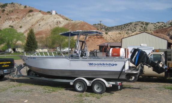 Wooldridge boat on trailer with Atlantic Towers T-Top installed, parked near a storage building and desert hills.